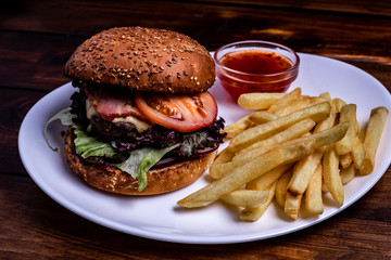 Cheeseburger close up. Burger with vegetables and French Fries. Vintage rustic style.