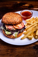 Hamburger close-up on black background. Fresh vegetables and grilled meat.