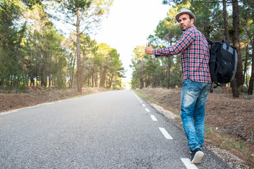 Man hitchhiking with thumbs up in a countryside road