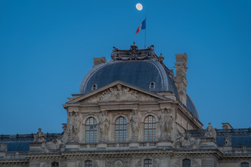 Fototapeta na wymiar Paris, France - 02 17 2019: The roofs of the buildings of the Louvre Museum at sunset with moon