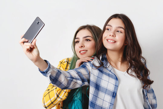 two young women taking selfie with mobile phone. on white
