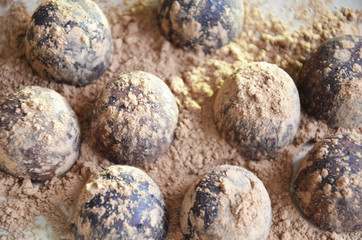 Chocolate candy truffle with chocolate pieces and flying cocoa powder on a dark background