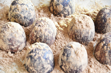 Chocolate candy truffle with chocolate pieces and flying cocoa powder on a dark background
