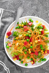 Fresh vegetable salad with raw carrot, green peas, corn, sweet pepper and lettuce. Healthy vegan, vegetarian lunch menu. Top view