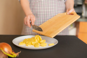 housekeeper puts sliced potatoes on a plate