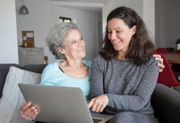 Happy senior woman and her daughter using laptop computer