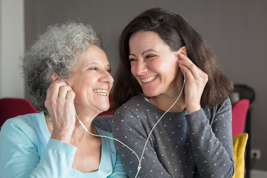 Happy senior woman and her daughter listening to music together