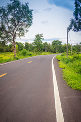 Fototapeta premium New asphalt winding curve road in the countryside with perspective white line and cloudy blue sky background.