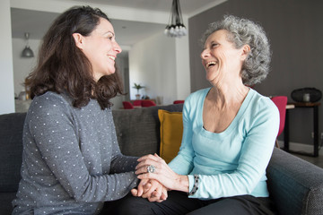 Positive elderly woman and her daughter chatting, laughing