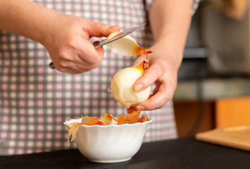 woman in the kitchen is cutting onions for dinner