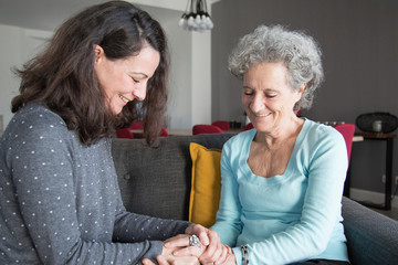 Smiling elderly woman and daughter chatting at home