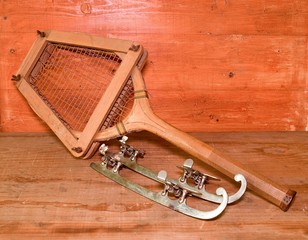 Fototapeta premium Vintage ice skates and tennis racket on wooden background. Retro ice skates and tennis racket.