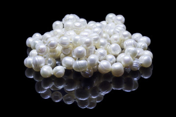 Natural white pearl beads on a black background with reflection