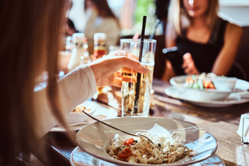 Young friends dine in the cafe outdoors. Close-up image of a table with different dishes and drinks