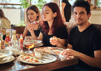 Young friends enjoying pizza and salad in a outdoor cafe