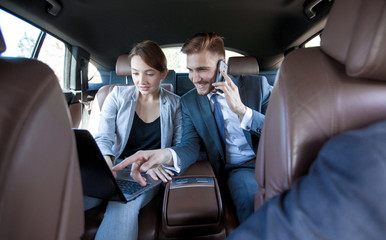business colleagues use a laptop to work in the car