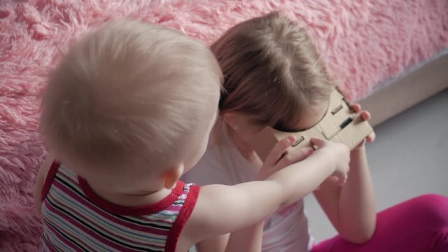 Young girl uses virtual reality VR cardboard, a device with which one can experience virtual reality on a mobile phone.