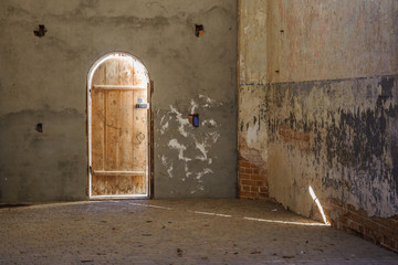 A ray of sunshine on a brick wall of a monastery through a slightly open door.