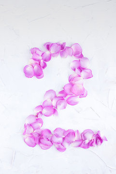 The figure 2 of rose petals on a white background. Pink roses for women's holiday. Photo or postcard in the concept of a romantic gift. Free place for text. Isolated image.