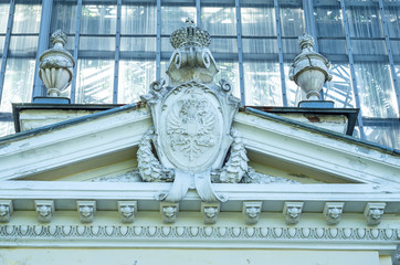 Stucco decor of an old mansion. Baroque monogram coat of arms of the royal family. The white facade...