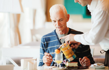 a waiter pouring tea for client of restaurant