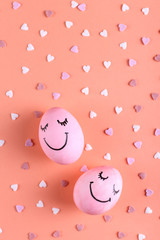 Pink eggs with painted smiles on the background with hearts, copy space. Happy Easter concept greeting card design.