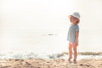 Child kid girl on beach looking into the distance searching for something with bright sunlight concept happy childhood lifestyle 