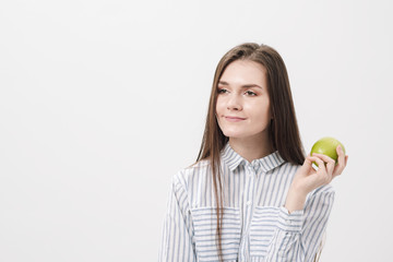 Young beautiful brunette girl on a white background holding a fresh green apple.