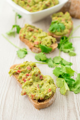 Fresh avocado cream or guacamole on wholemeal slices, healthy breakfast concept.
