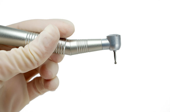 dental handpiece in the hands of the dentist isolated on white background close-up, dental drill, burr