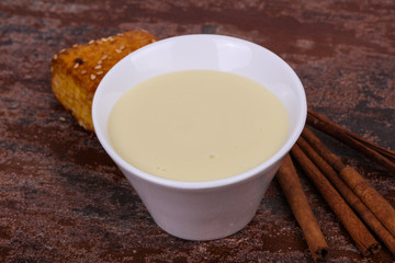 Condenced milk in the bowl with sinnamon and pastry