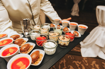 Waiter carrying diversity of mousse desserts on some festive event, party or wedding reception