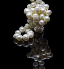 Natural white pearl beads on a black background with reflection