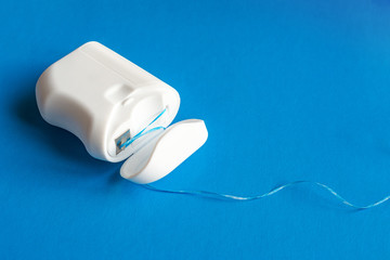 dental floss  on a blue background, the concept of care for the oral cavity, preventing tooth...