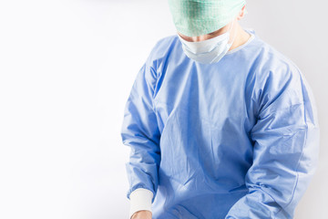Surgeon doctor in sterile gloves preparing for operation in hospital. He is wearing surgical cap and blue gown