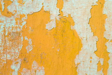 Contrast photograph of an old yellow wall with defects and remnants of fragments of light abstract plaster
