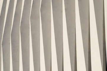 Obraz premium Wave facade of the building. White graphical linear facade of the building. The play of light and shadow. Neutral fashionable background. Light stripes.