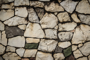 Vintage nature cobblestone wall in disorganized arrangement pattern background. Fence wall made of nature asymmetrical stone background.