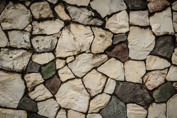 Vintage nature cobblestone wall in disorganized arrangement pattern background. Fence wall made of nature asymmetrical stone background.