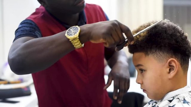 Boy in the african barbershop. Cute mixed boy makes a haircut in the African salon. Hair style. Haircut by machine for children. School boy hair style. Haircut 