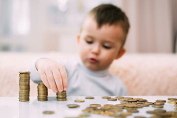 Junge schaut sich Geldstapel an, die auf einem Tisch liegen