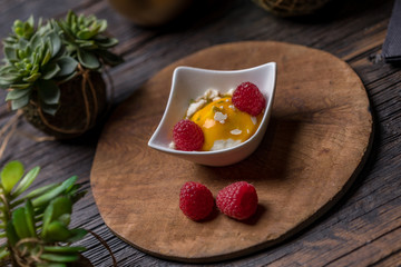 Cream fruit dessert with mango passion fruit sauce and raspberries and meringue 