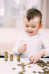 Junge schaut sich Geldstapel an, die auf einem Tisch liegen