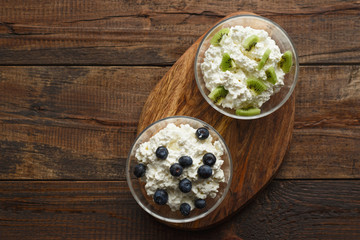 Obraz na płótnie Canvas Top view cottage cheese blueberries and kiwis on wooden stand with natural light with copy space