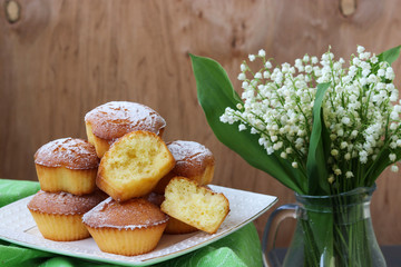Cupcakes with semolina on kefir on a white plate.Nearby is a jug with lilies of the valley