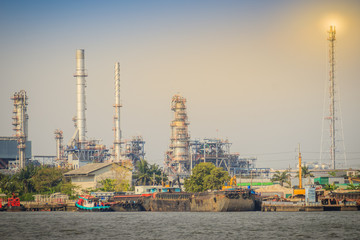 Fototapeta na wymiar Oil refinery plant at riverfront of Chao Phraya river in Bangkok, Thailand. Heavy industrial oil refinery riverfront with daylight and blue sky background.