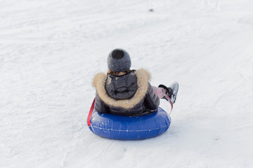 winter, leisure, sport, friendship and people concept - group of happy people sliding on the snow...