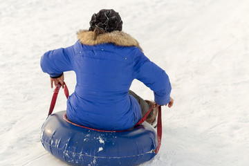 winter, leisure, sport, friendship and people concept - group of happy people sliding on the snow...
