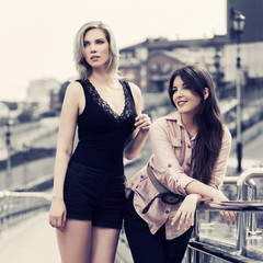 Two happy young fashion women walking on city street