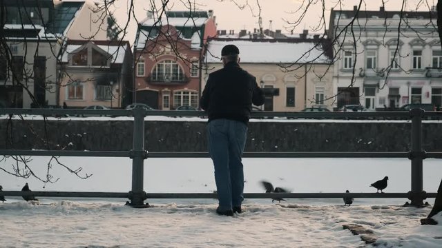 A man feeds pigeons on the city embankment. Slow motion. 4k